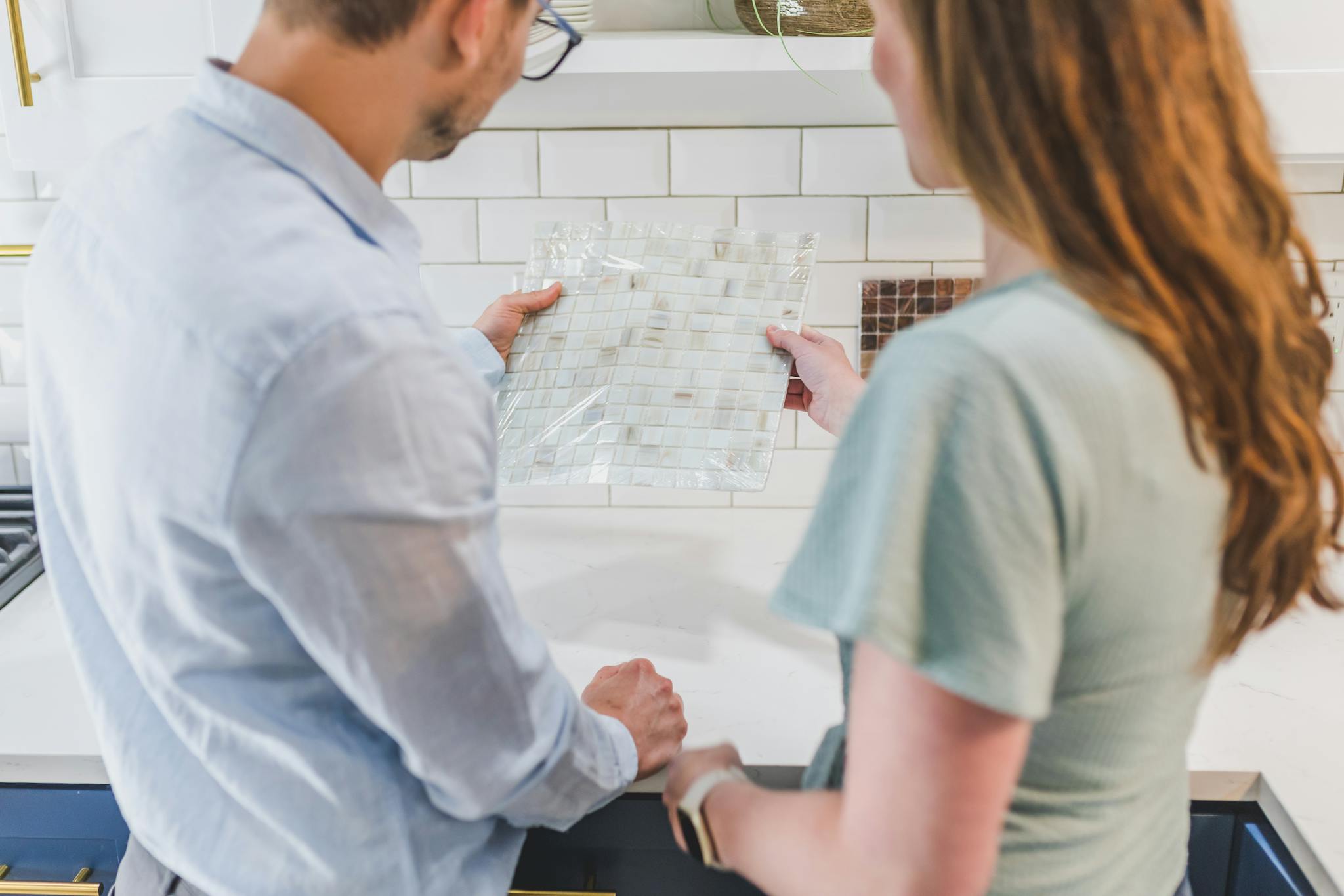 A man and woman selecting tile designs for a kitchen remodeling project.