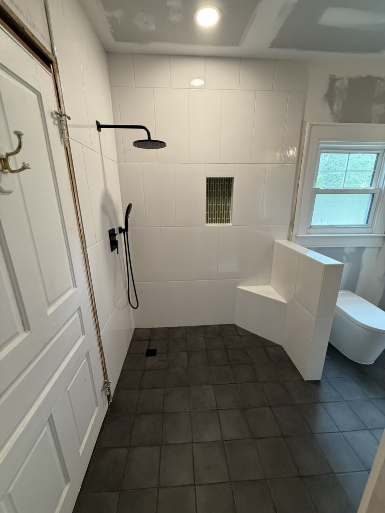 Finished glass walk-in shower with black fixtures in Clayton NC bathroom